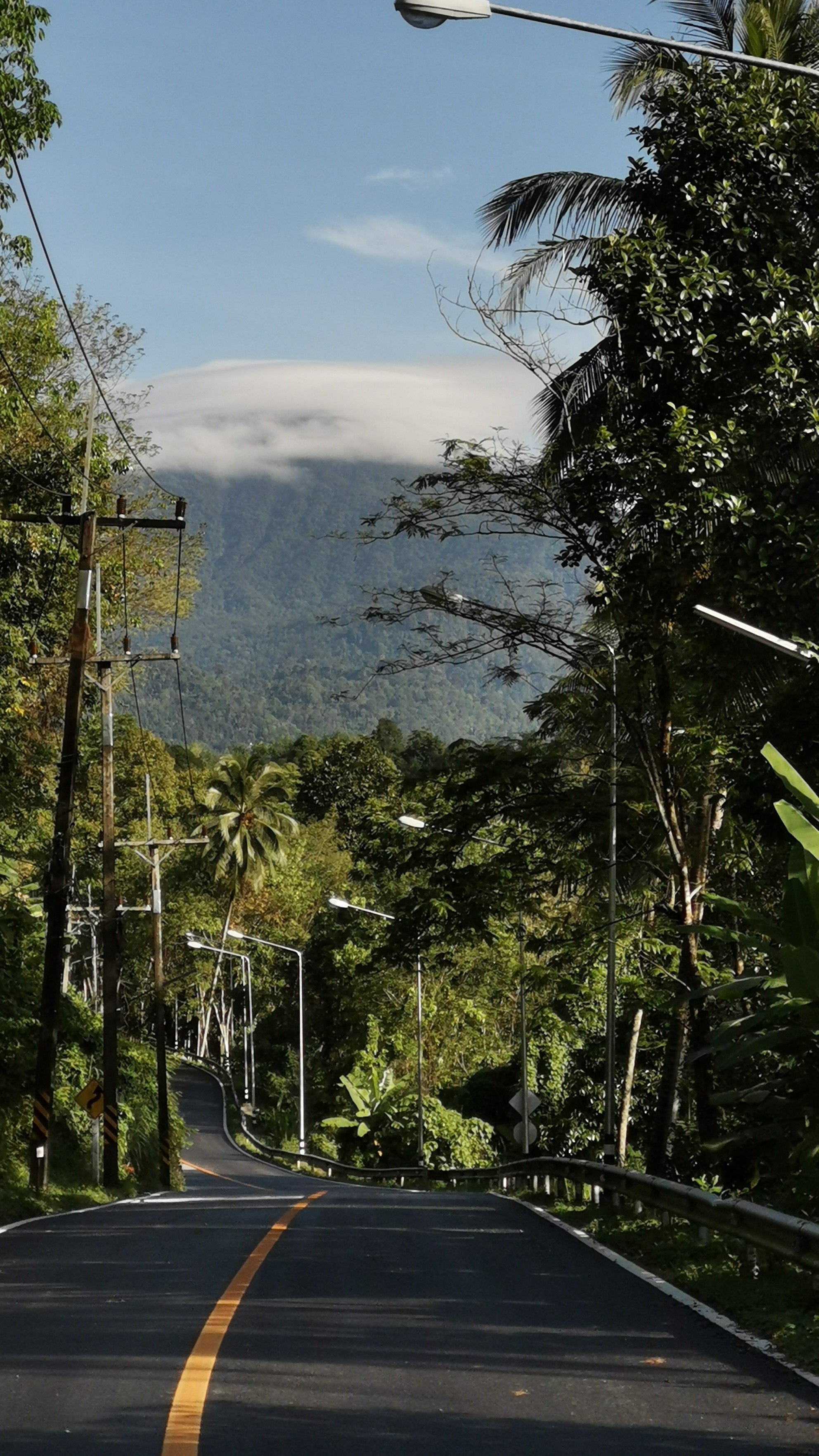 The Mountain Beckons: The welcoming cloud-capped peaks of Khao Luang mountain beckoning travelers on the winding road to Baan Khiri Wong.